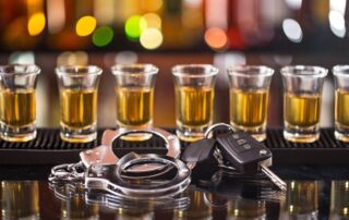 DUI vs DWI What Is the Difference in Morgan County Georgia Portrayed by shot glasses on a bar top, handcuffs and car keys.